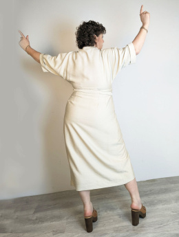 Kremowa sukienka z wąską talią, prostym dołem i kopertowym fasonem na modelu JOANNA